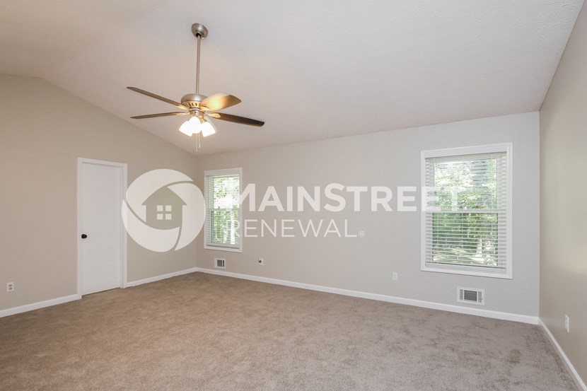 an empty living room with a ceiling fan and a window