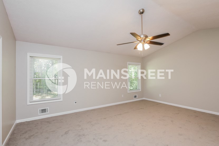 a large empty living room with a ceiling fan