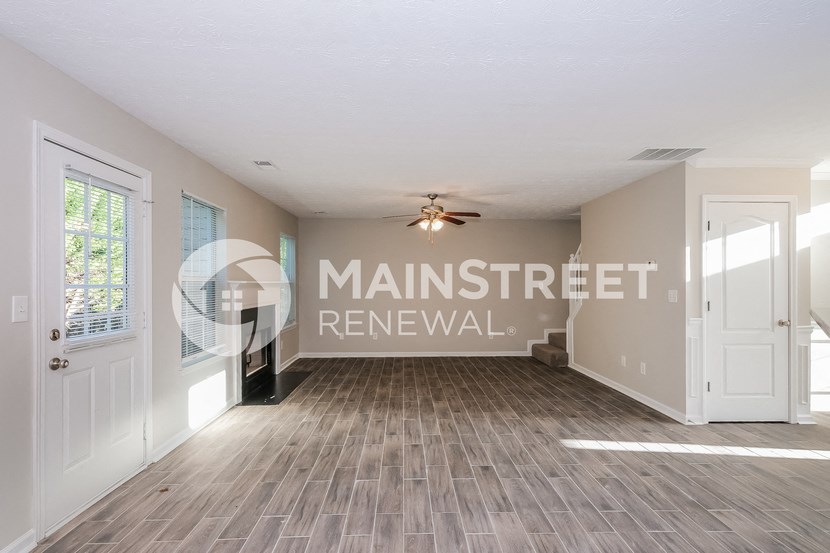 an empty living room with a white door and a ceiling fan