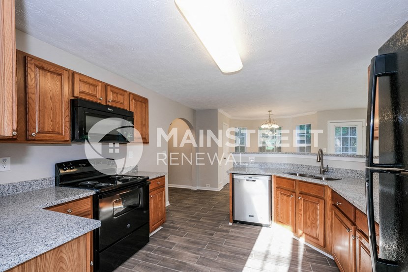 a kitchen with wood cabinets and black appliances and a counter top