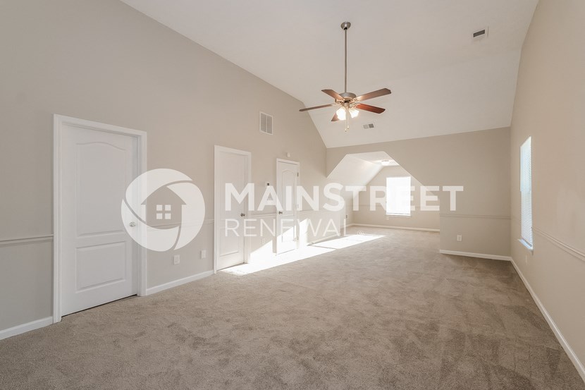a living room with carpet and a ceiling fan
