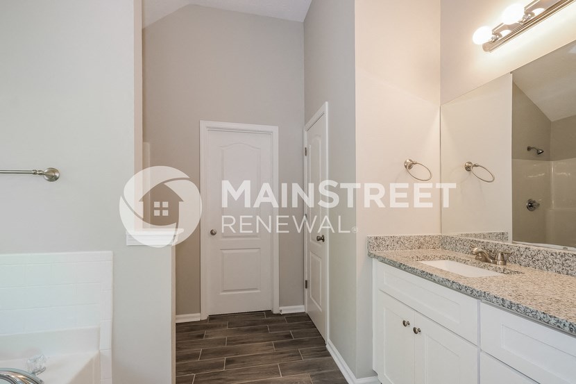 a bathroom with white cabinets and a sink and a mirror