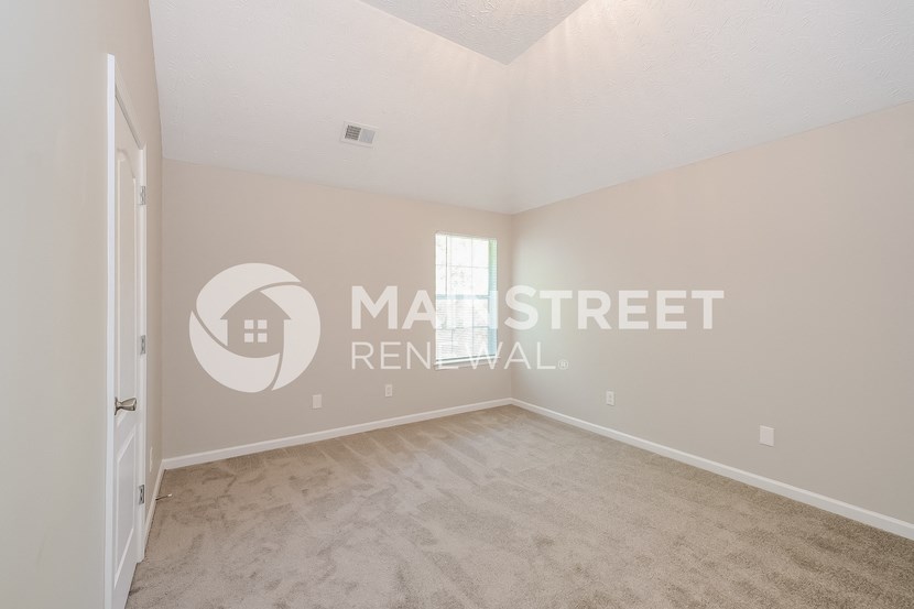 a bedroom with beige carpet and white walls