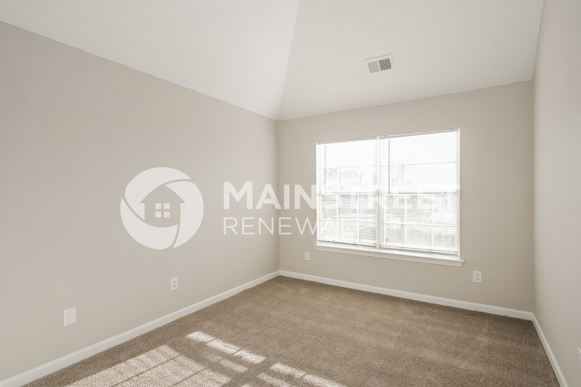 a bedroom with a carpeted floor and a large window