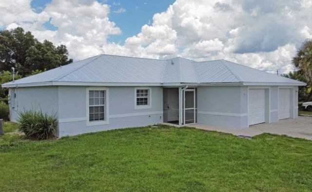 A white house with a grey roof and a green lawn in front.