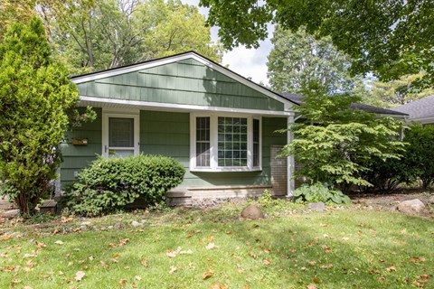 A green house with a white window and a small porch.
