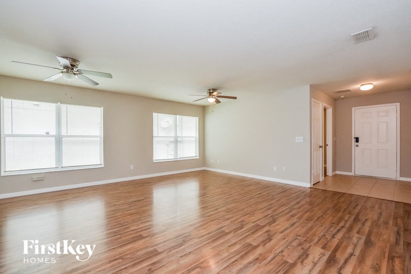 A spacious room with wooden floors and two ceiling fans.