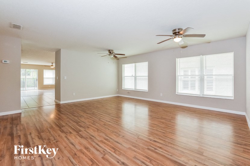 A spacious room with wooden flooring and a ceiling fan.