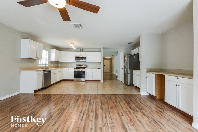 A spacious kitchen with wooden floors and white cabinets.