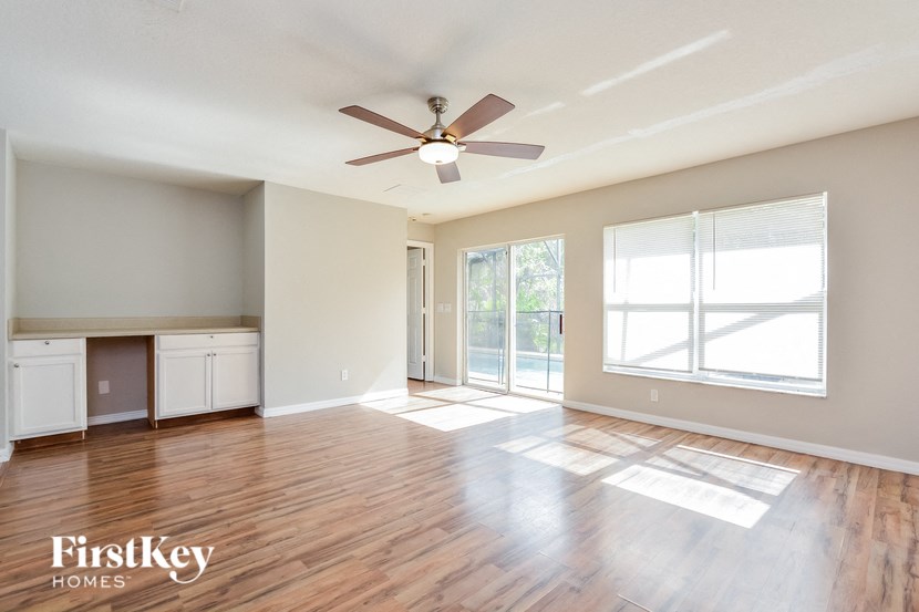 A spacious room with wooden floors and a ceiling fan.