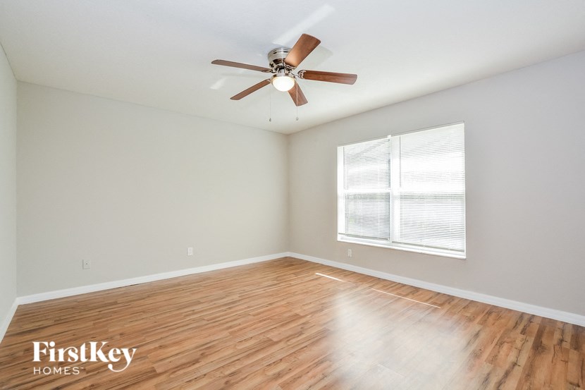 A room with a ceiling fan and wooden flooring.