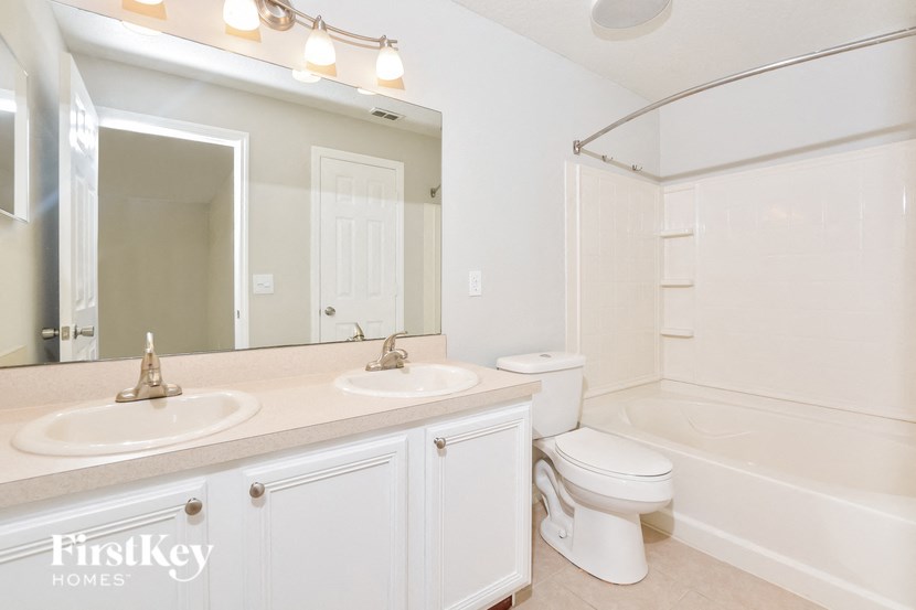 A white bathroom with a double sink vanity and a toilet.
