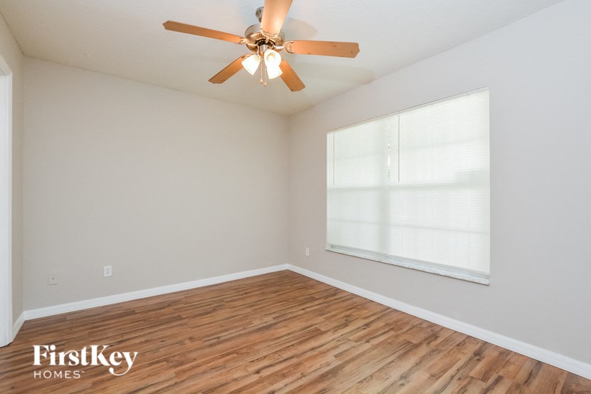 A room with a ceiling fan and wooden flooring.