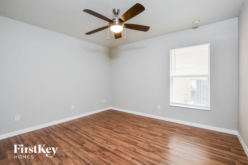 A room with a ceiling fan and wooden flooring.