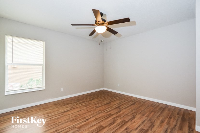 A room with a ceiling fan and wooden flooring.