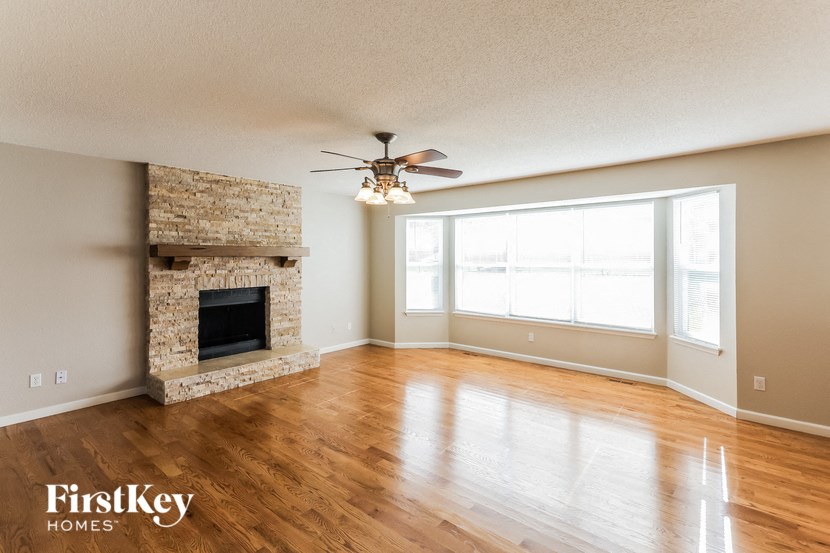 an empty living room with a fireplace and a ceiling fan