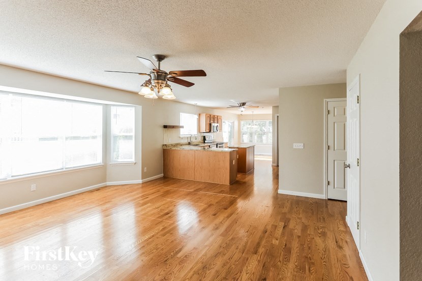 an empty living room and kitchen with a ceiling fan