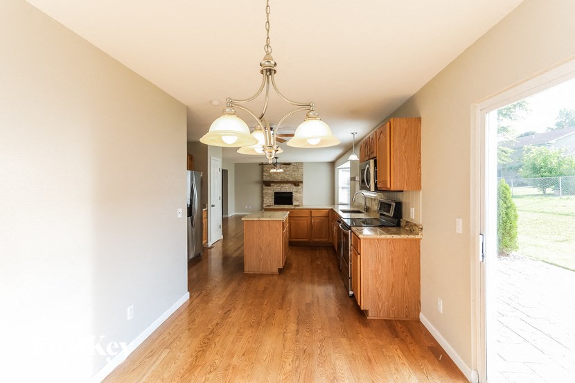 a large kitchen with wooden floors and a chandelier