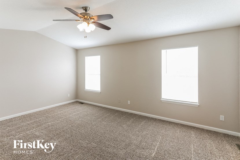 a empty room with a ceiling fan and two windows