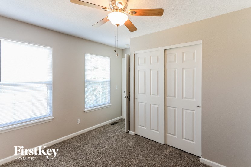 a bedroom with a ceiling fan and two windows