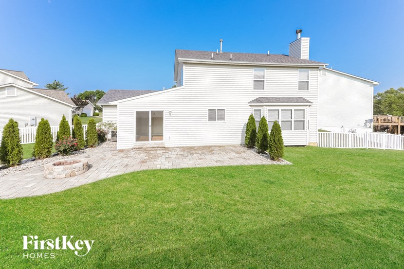 a backyard with a white house and a grassy yard
