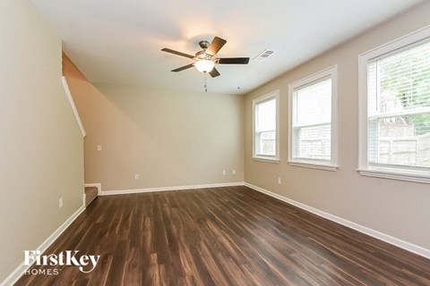 an empty living room with a ceiling fan and three windows