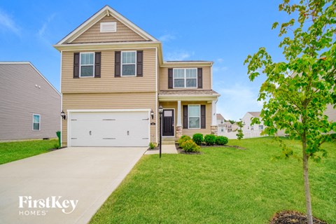 a tan house with a white garage door on a green lawn