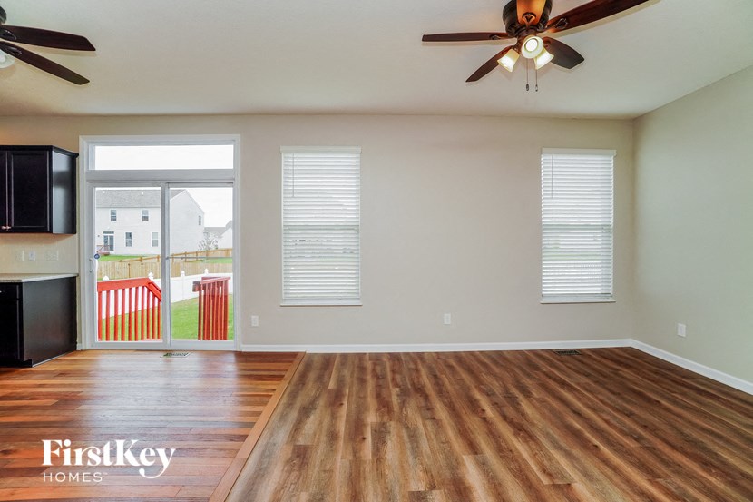 an empty living room with wood floors and a ceiling fan