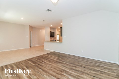A spacious room with wooden flooring and a white wall.