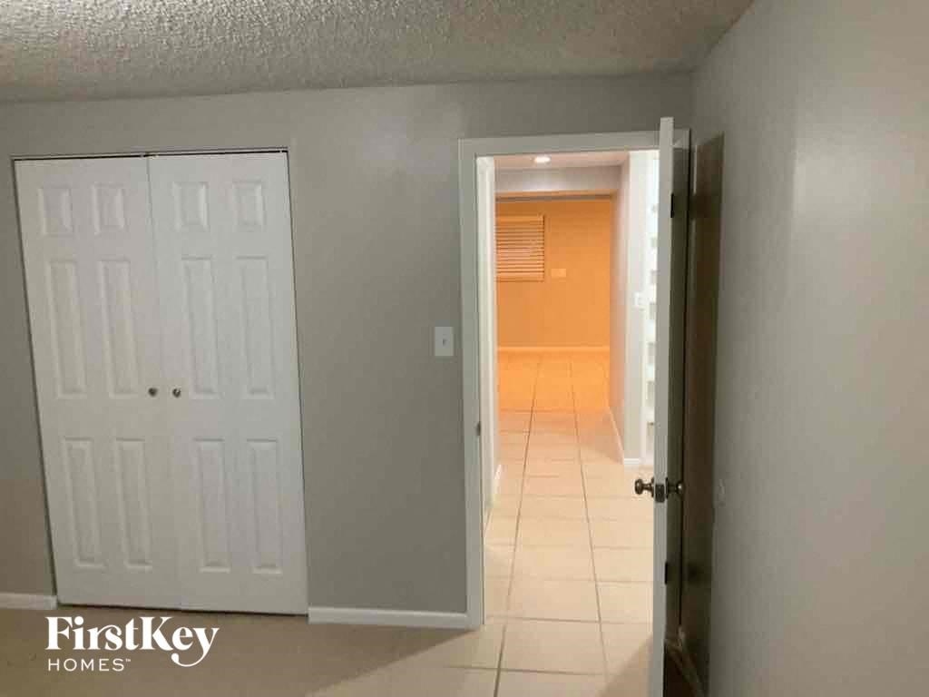 an empty hallway with a white tile floor and a white door