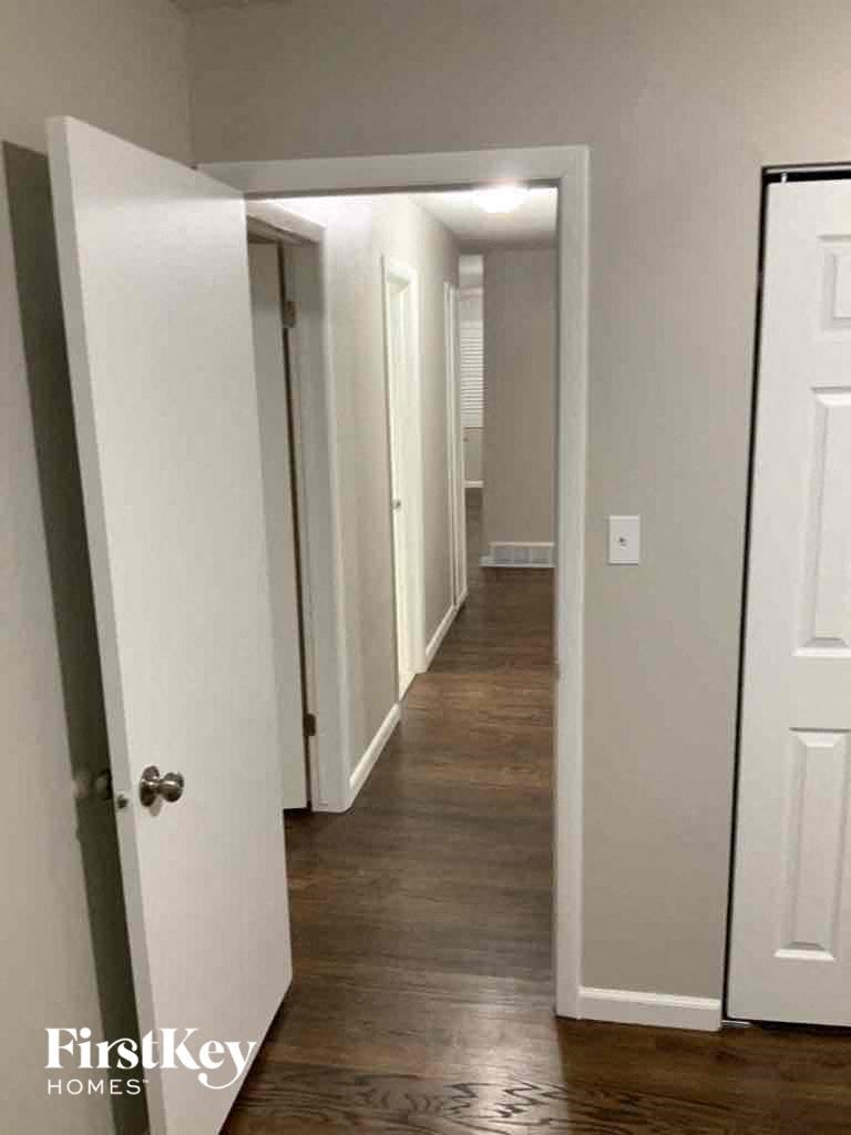 a hallway in a home with white walls and wood floors