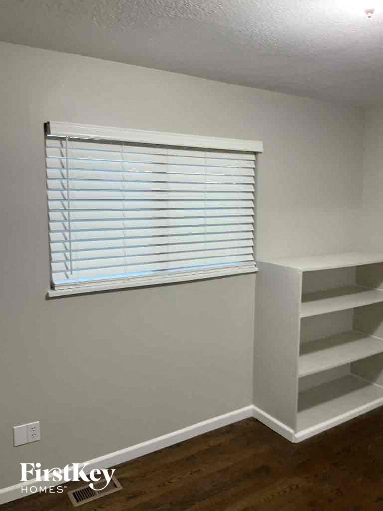 a room with white shelves and a window with blinds