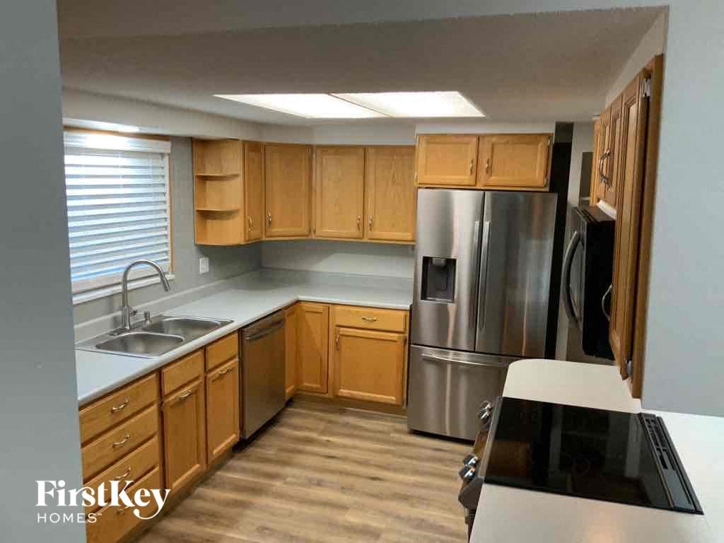 an empty kitchen with wooden cabinets and a stainless steel refrigerator