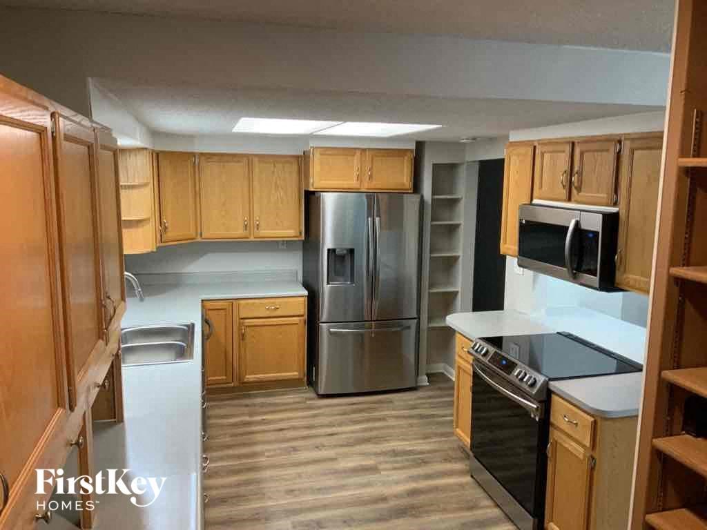 an empty kitchen with wooden cabinets and a stainless steel refrigerator