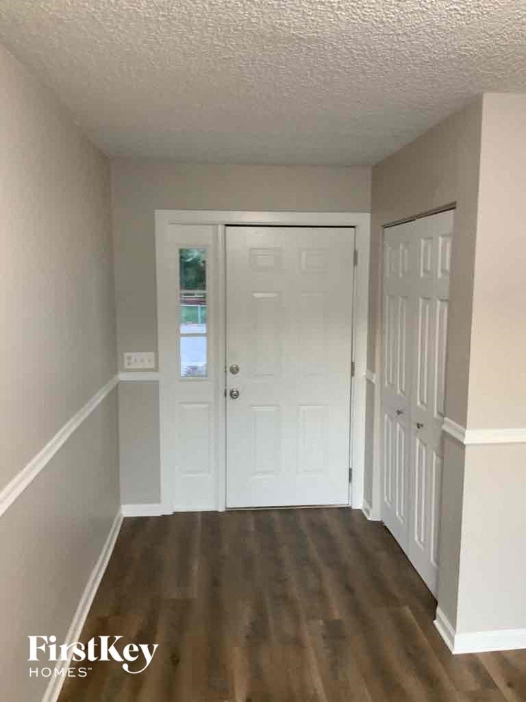 a room with a white door and a hallway with wooden floors