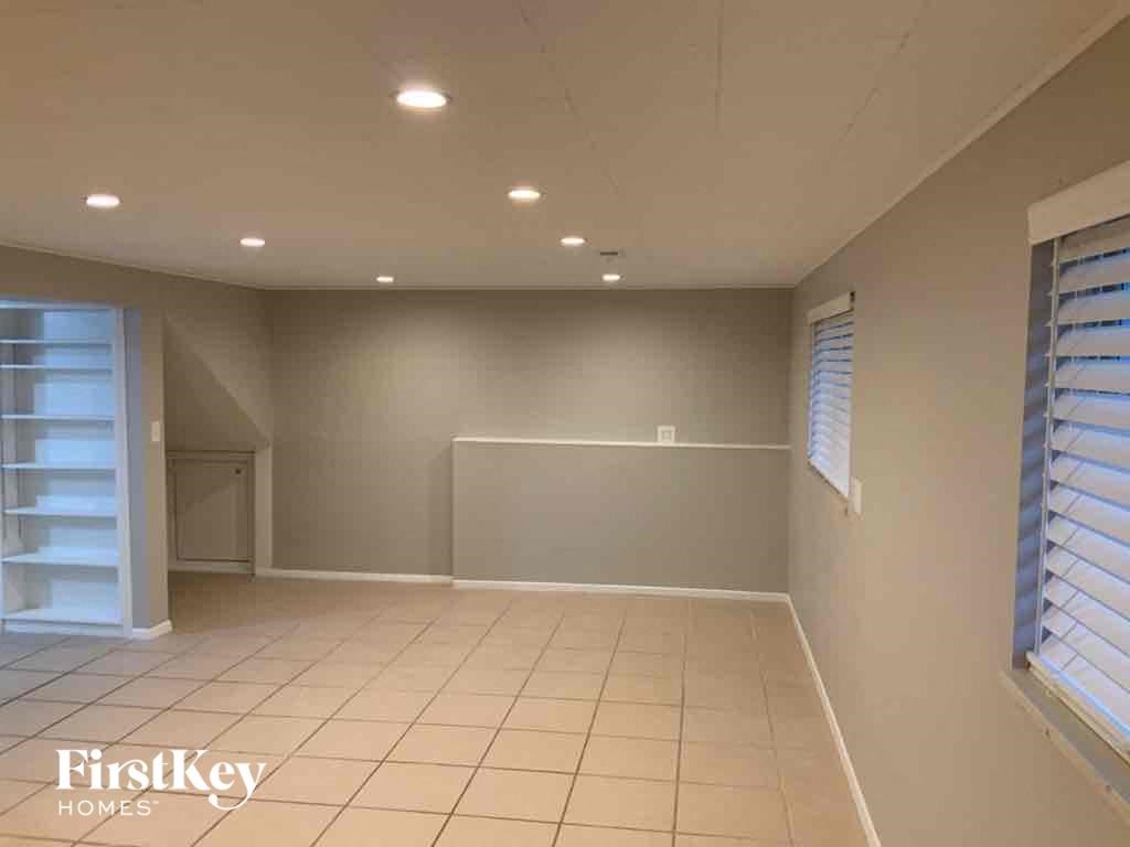 an empty living room with a tile floor and a door to a closet
