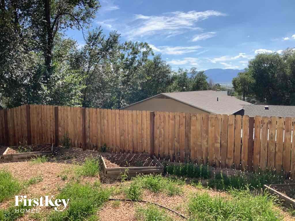 a backyard with a wooden fence and a house behind it