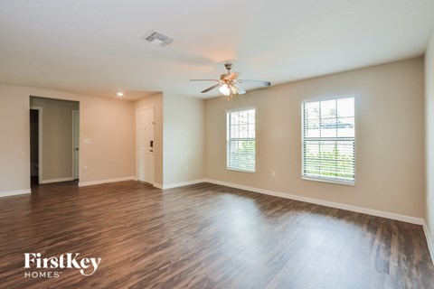A spacious room with wooden floors and a ceiling fan.