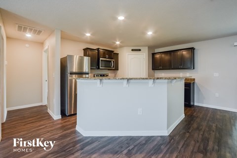 A kitchen with a white island in the middle and wooden floors.
