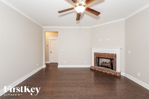 a empty living room with a ceiling fan and a fireplace