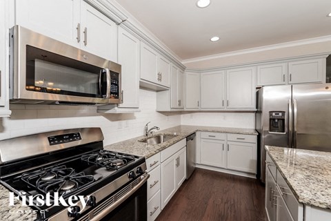 a white kitchen with stainless steel appliances and marble counter tops