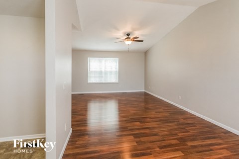 an empty living room with wood flooring and a ceiling fan