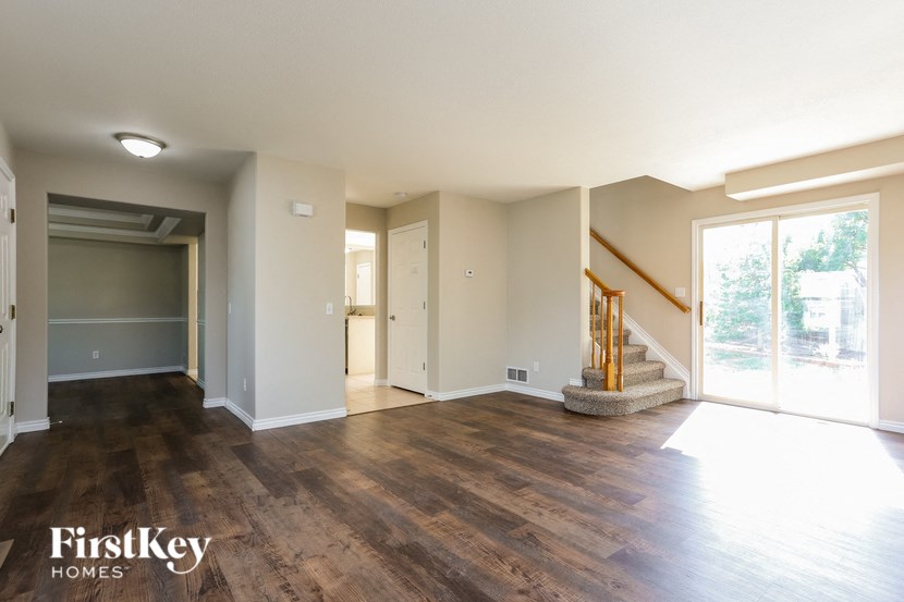 A spacious room with wooden floors and a staircase leading to another room.