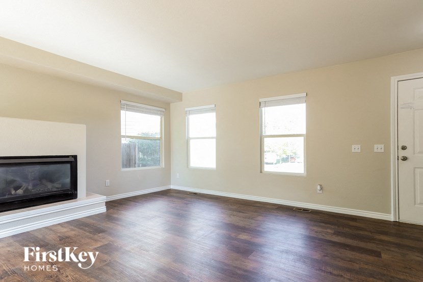 A spacious room with a fireplace and wooden floors.