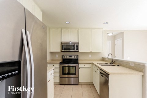 A kitchen with a stainless steel refrigerator and white cabinets.