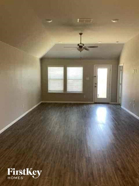 an empty living room with a ceiling fan and wood floors