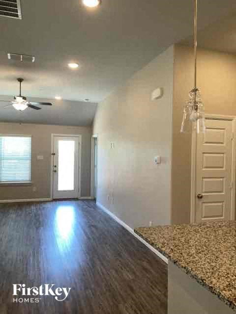 an empty living room with a white door and a ceiling fan