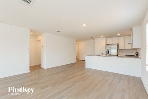 A spacious kitchen and living room with wooden flooring and white walls.