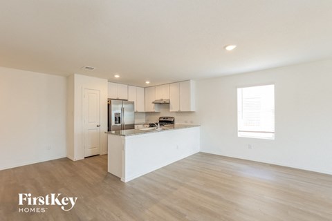 A spacious kitchen with white cabinets and a wooden floor.