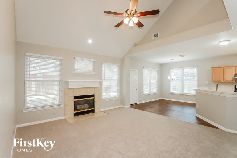 an empty living room with a fireplace and a ceiling fan